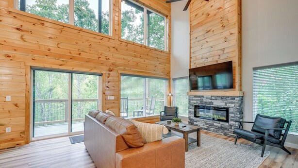 Ein geräumiges Wohnzimmer mit einer großen Holzbalkendecke, einem Kamin aus Stein und einem Ledersofa.