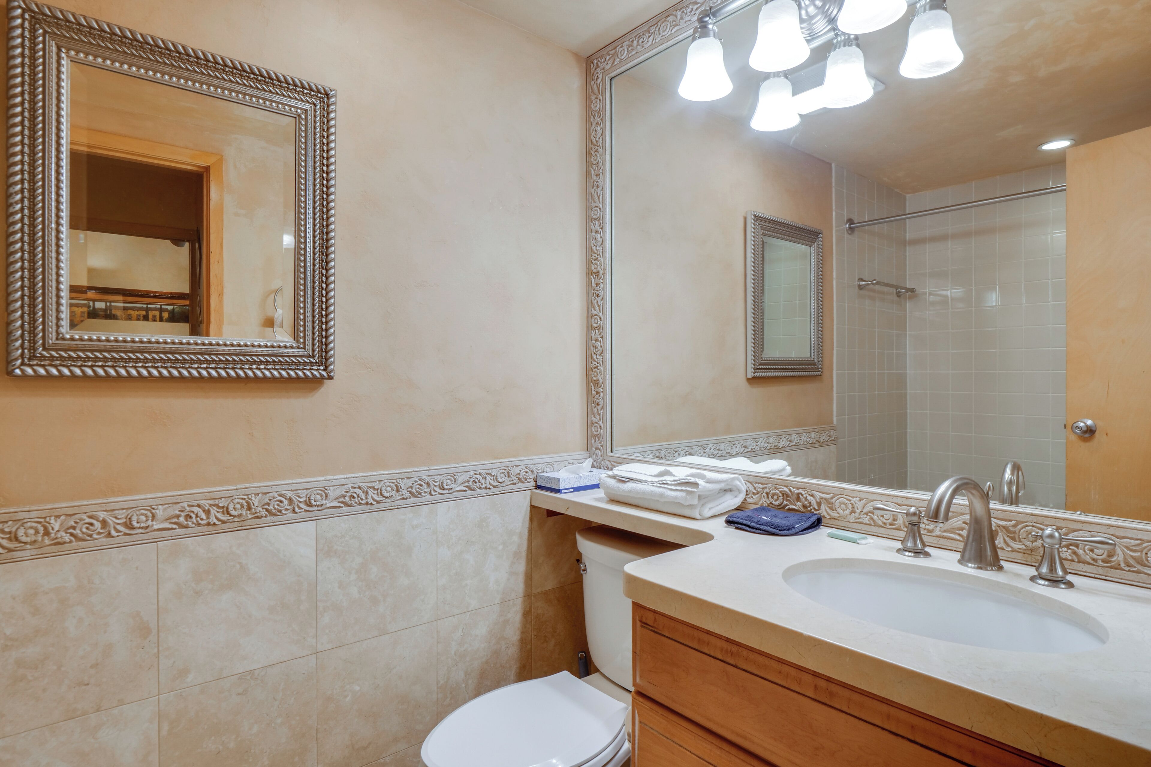A bathroom with a large mirror, a sink, and a toilet.