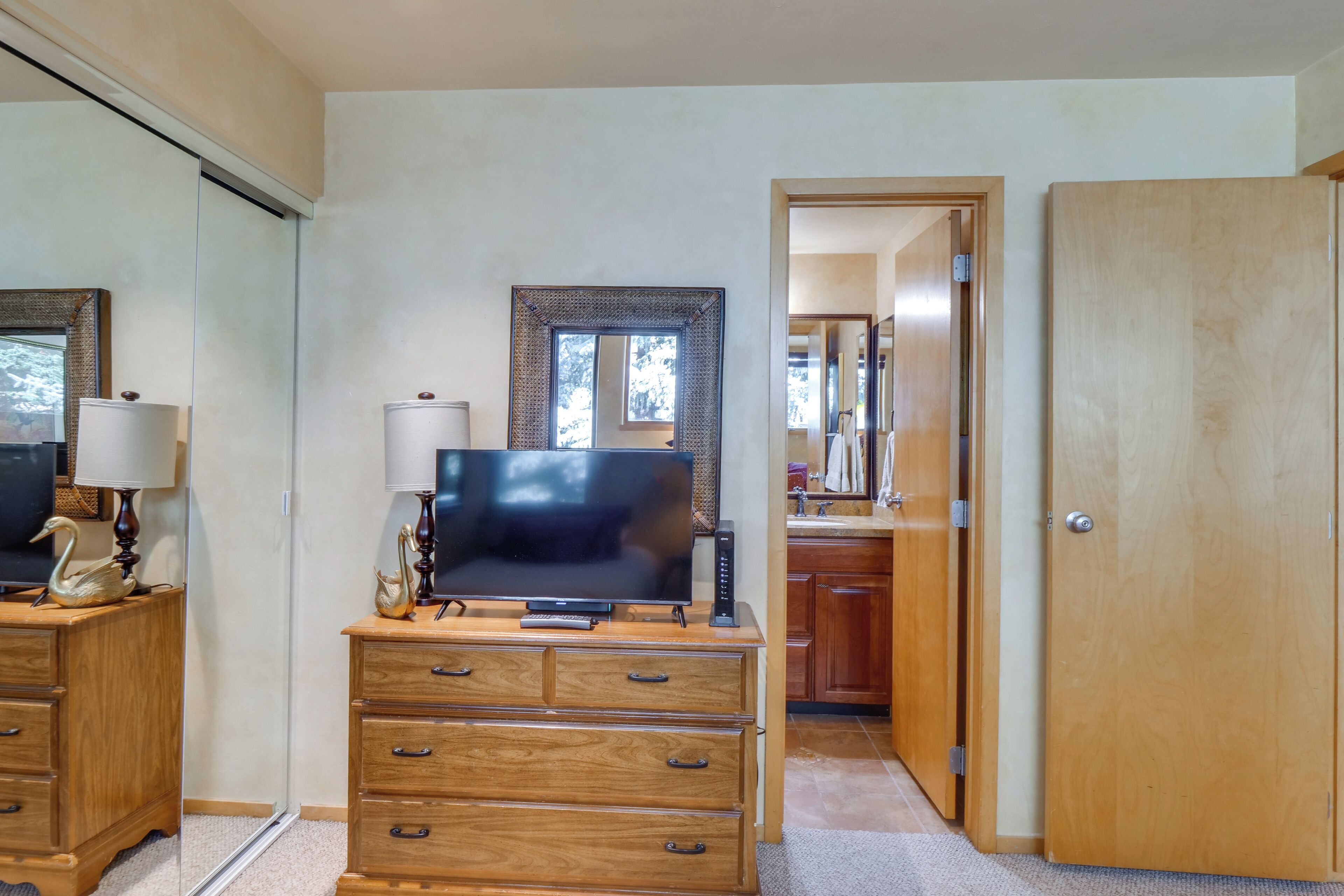 Een kamer met een houten dressoir, een flatscreen televisie en een spiegel.