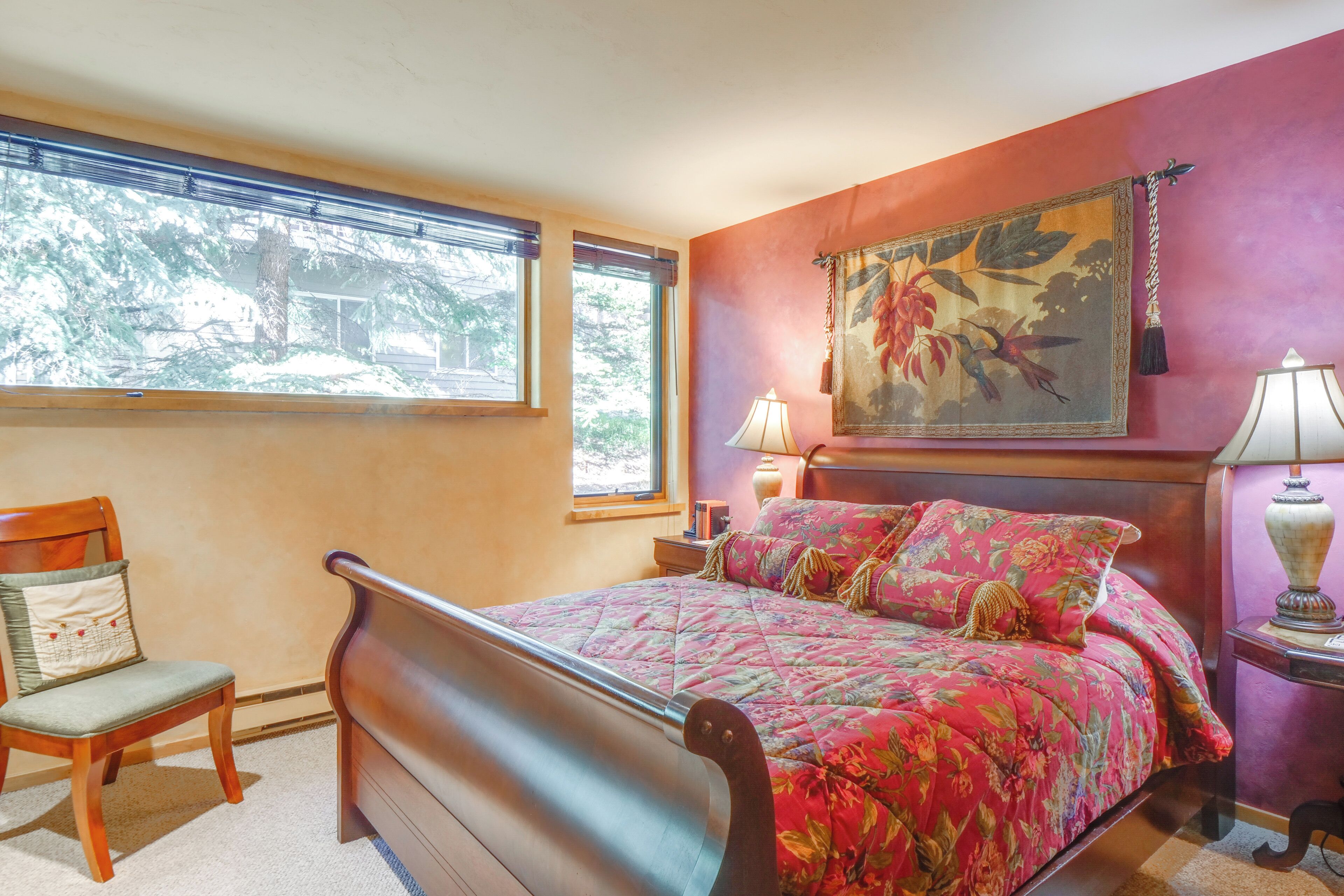 Een slaapkamer met een bed, een stoel, een raam en een schilderij aan de muur.