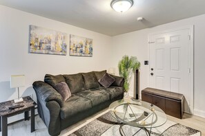 A living room with a dark green sofa, a glass coffee table, a small side table, and a potted plant. - < 2 Mi to Umass Health & Dtwn: Traveling Pros Hub (Worcester)
