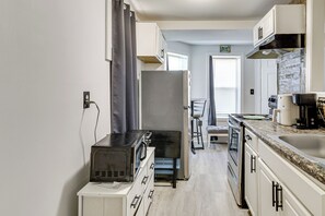 A compact kitchen with a microwave, refrigerator, and stove. There is a window with curtains, a sink, and a chair. - < 2 Mi to Umass Health & Dtwn: Traveling Pros Hub (Worcester)
