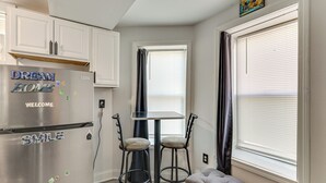 A compact kitchen with a stainless steel refrigerator, two bar stools, a small dining table, and a bench. - < 2 Mi to Umass Health & Dtwn: Traveling Pros Hub (Worcester)