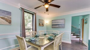 A dining area with a glass table, white chairs, and a ceiling fan. - Walk to Beach: Peaceful Hilton Head Island Condo (Hilton Head Island)