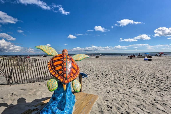 Une scène de plage avec une sculpture de tortue, un banc en bois et une clôture.