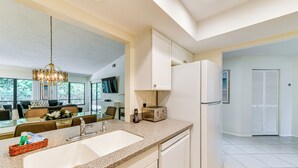 A modern kitchen with a granite countertop, white cabinetry, and a built-in dishwasher. - 4 Mi to Siesta Beach: Condo w/ Community Perks! (Sarasota)