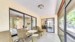 A sunlit patio with wicker chairs and a small table, large sliding glass doors leading to a kitchen, and a ceiling fan. - 4 Mi to Siesta Beach: Condo w/ Community Perks! (Sarasota)