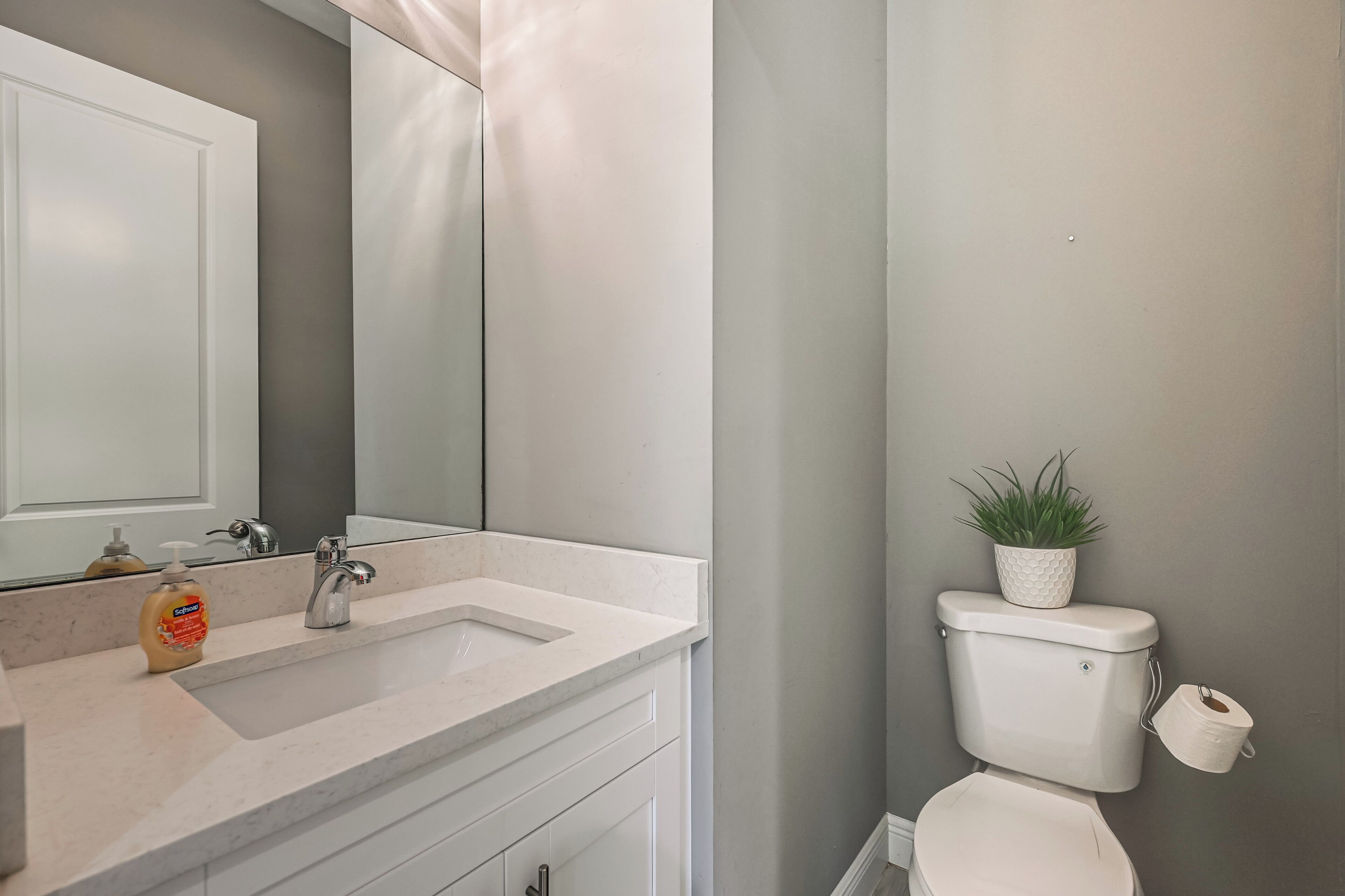 A bathroom with a white sink, mirror, and toilet.