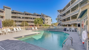 Un espace piscine d’hôtel doté de plusieurs niveaux de balcons, de chaises longues et d’un poste de surveillance pour les sauveteurs.