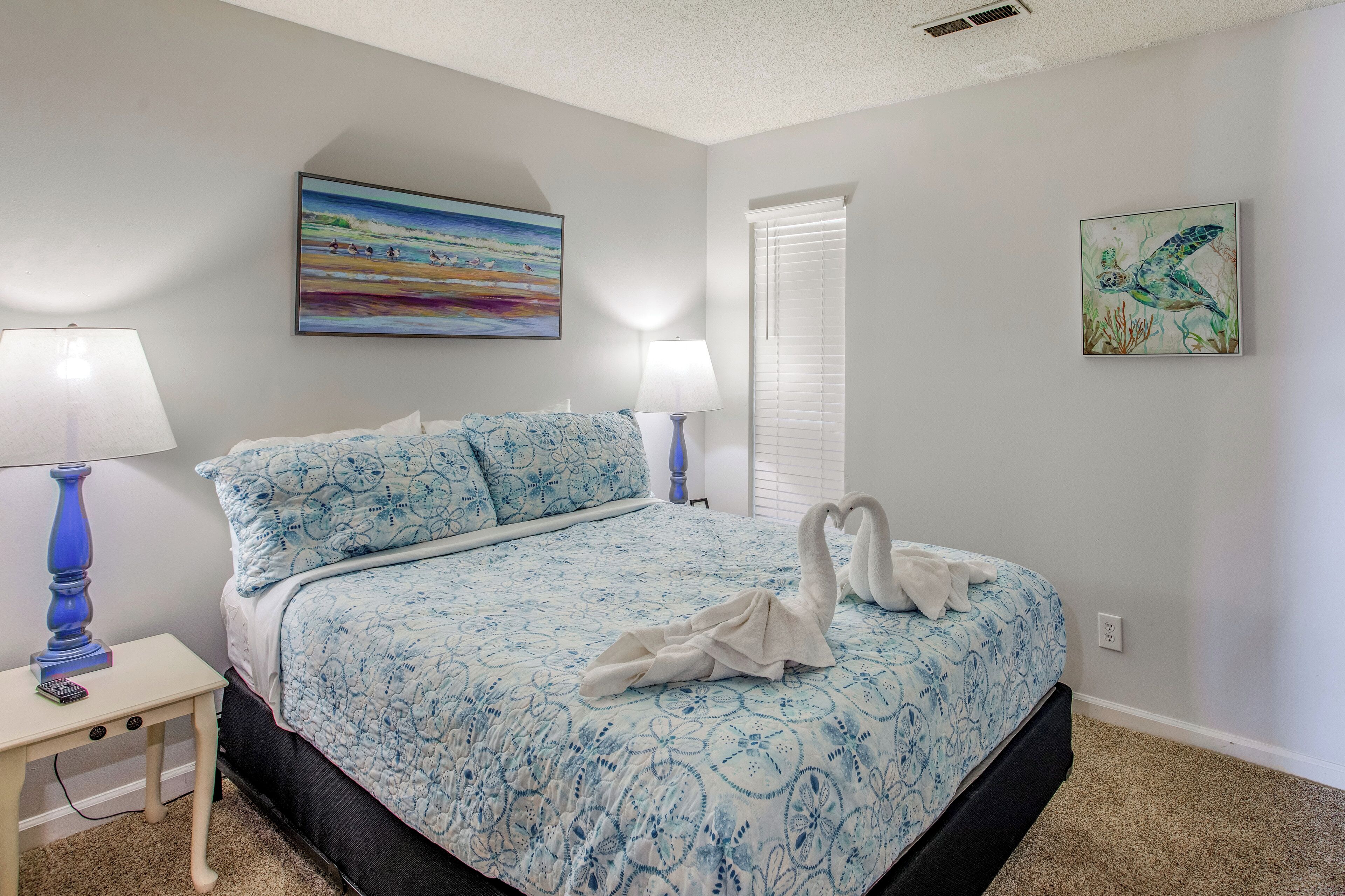 A bedroom with a bed, two bedside tables, and wall art.