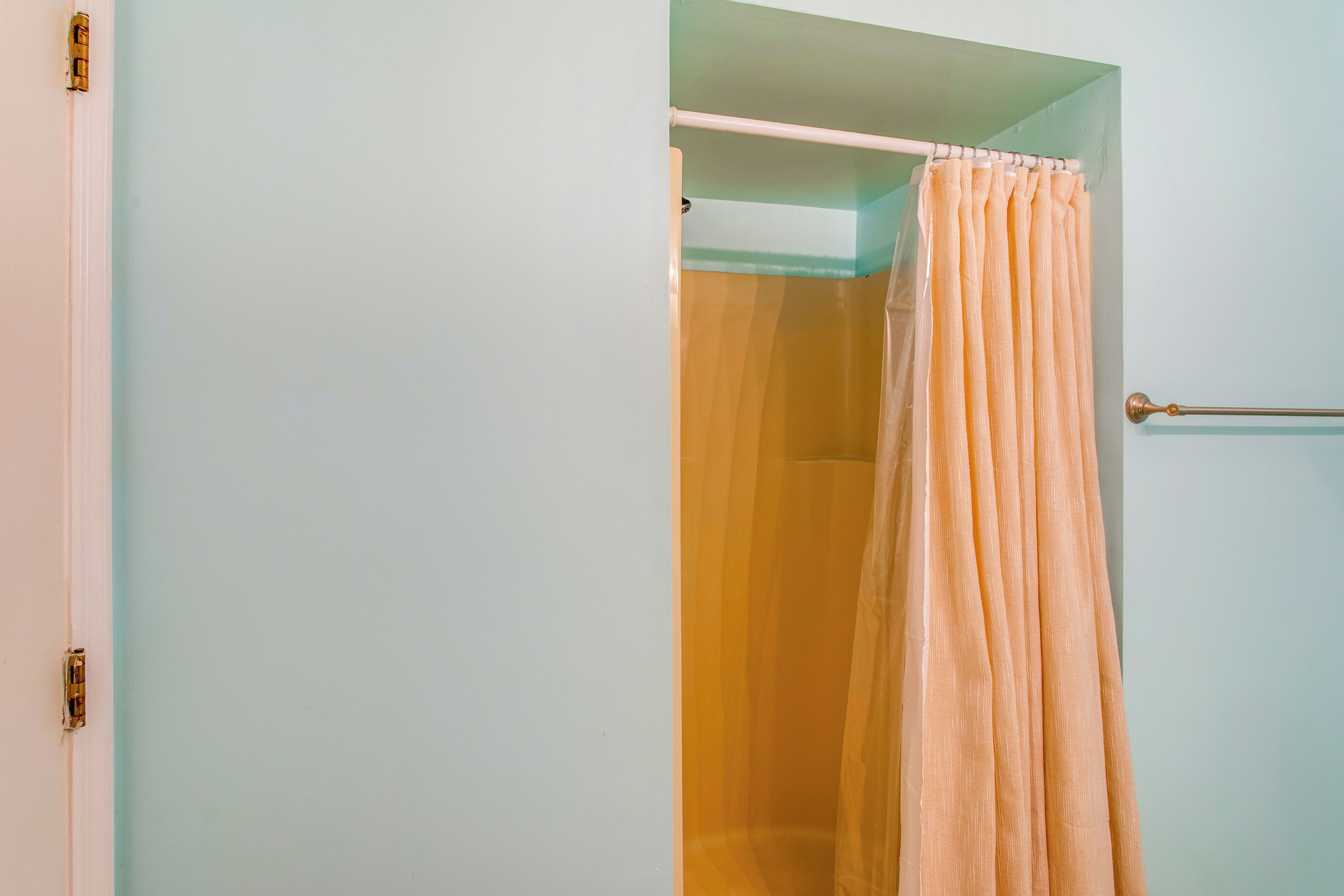 A bathroom with a shower curtain, a towel rack, and a door with a handle.