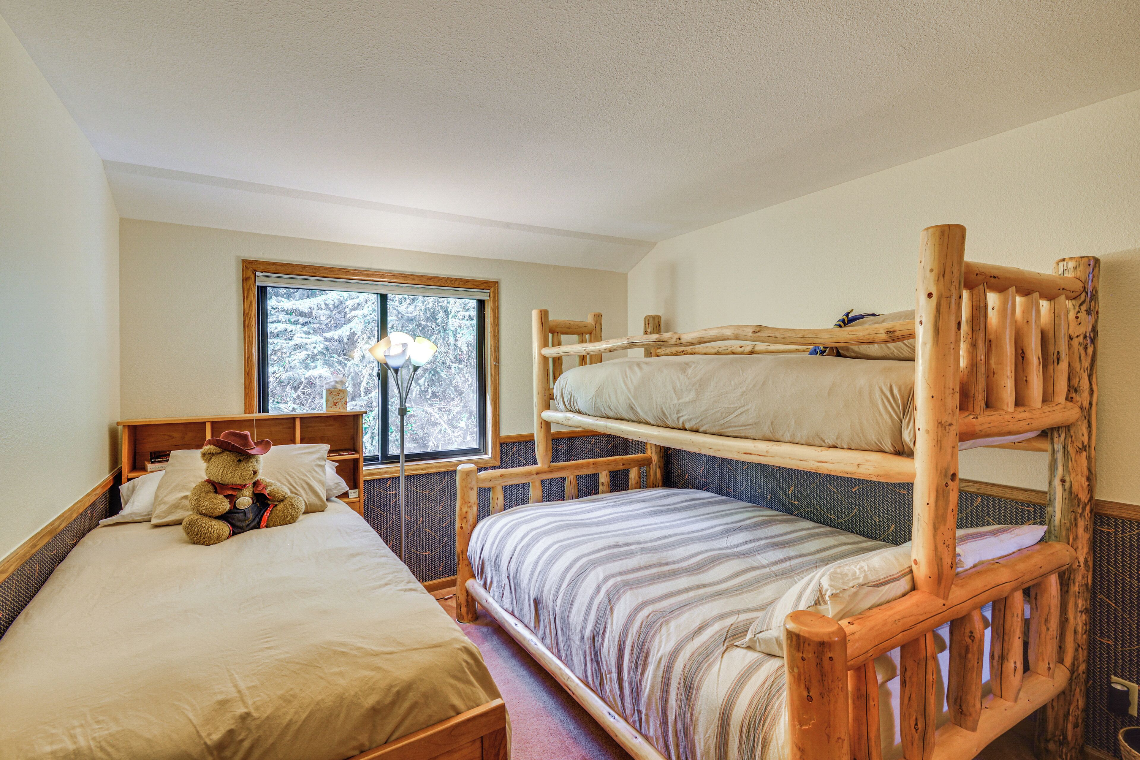 Une chambre avec deux lits superposés, une fenêtre donnant sur la forêt et un ours en peluche sur le lit du bas.