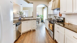 A modern kitchen with white cabinetry, a dishwasher, a stove, and a countertop with a sink. - 11 Mi to Texas Tech University: Cozy Family Home! (Wolfforth)