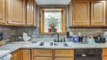 A kitchen with wooden cabinets, a granite countertop, a double sink, and a dishwasher.