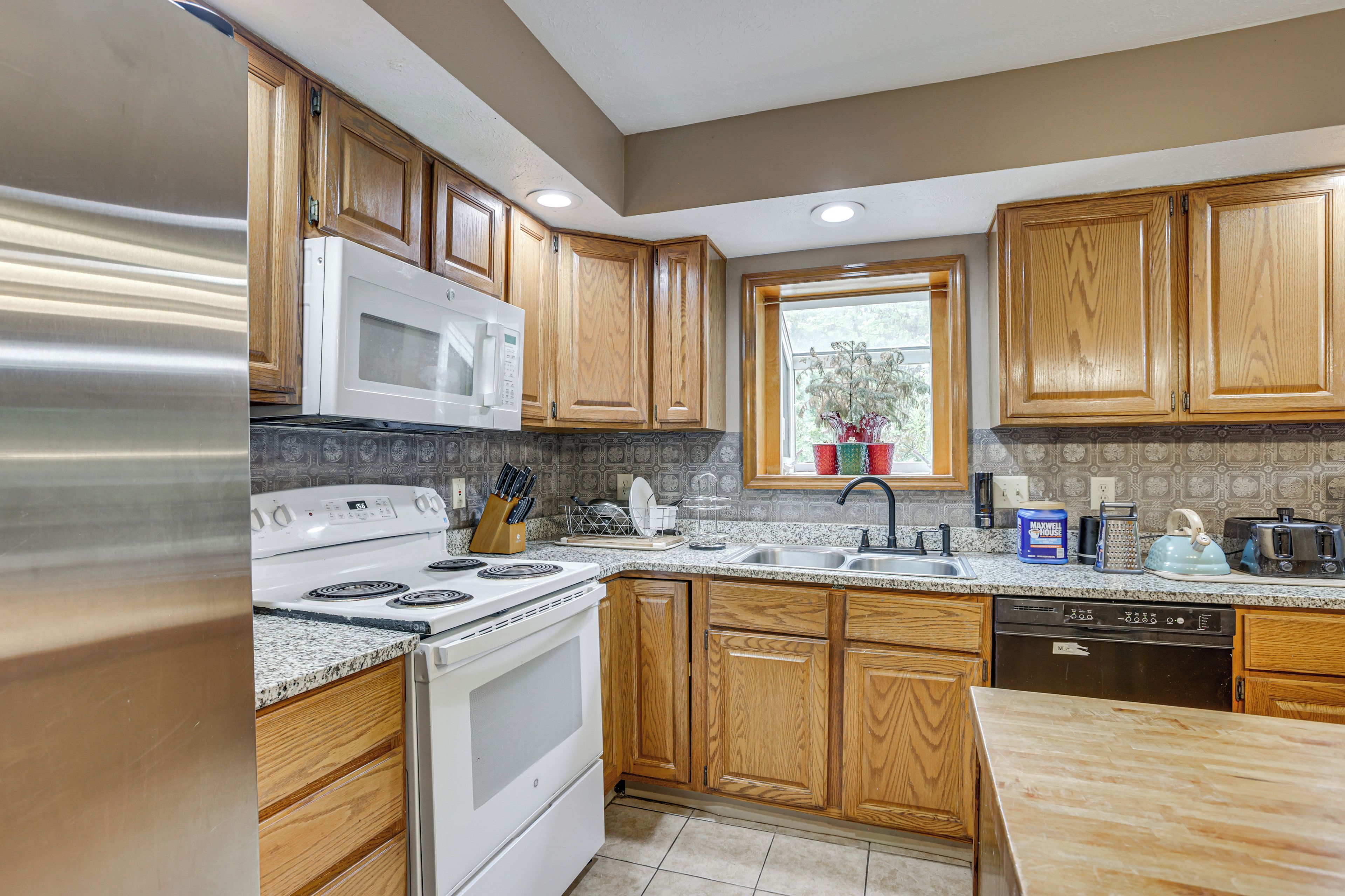 A modern kitchen with wooden cabinets, stainless steel appliances, and a granite countertop.