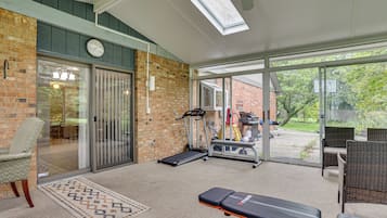A home gym with exercise equipment, a clock, and a view of the outdoors.