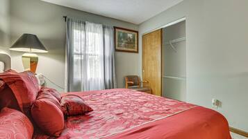 A bedroom with a bed, a chair, a lamp, a painting, and a door.