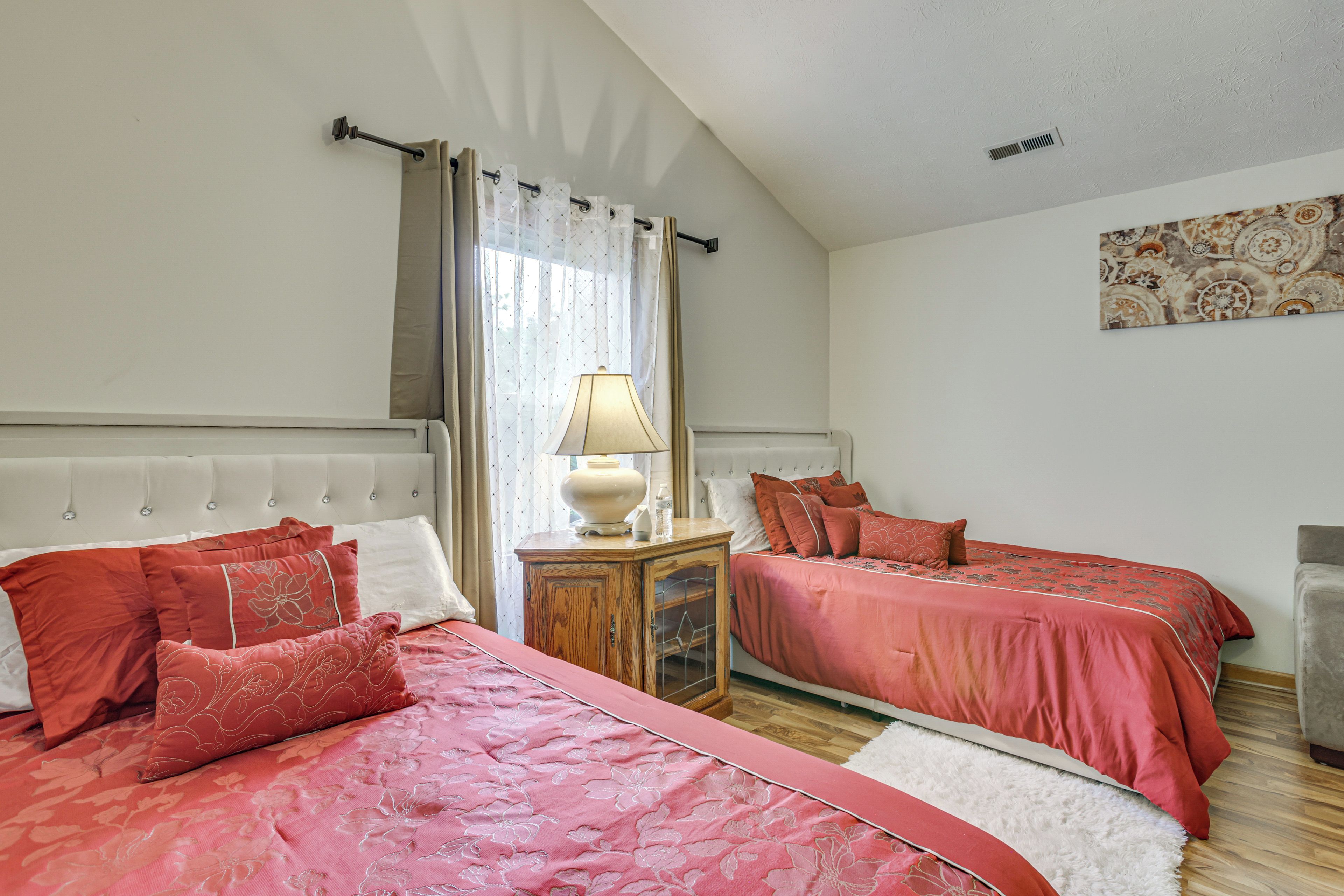 Un dormitorio con dos camas, una mesita de noche, una lámpara y una ventana con cortinas.
