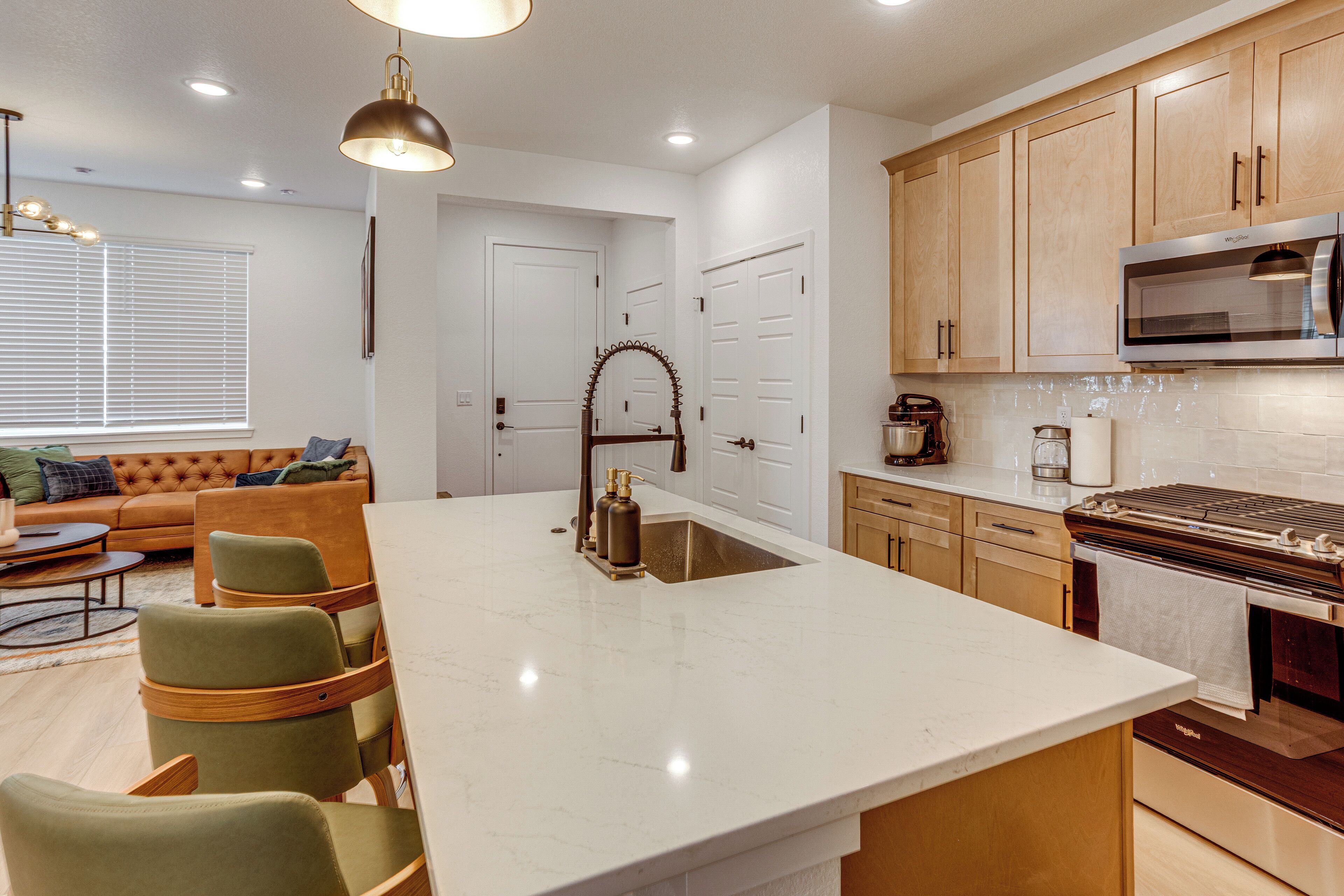 A modern kitchen with a large island, wooden cabinets, and stainless steel appliances.