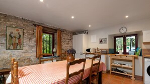 Una cocina rústica con paredes de piedra, una mesa de madera con mantel a cuadros y un reloj en la pared.