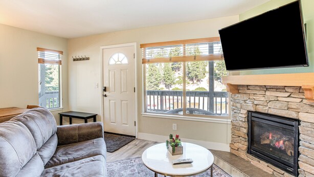 A living room with a gray sofa, a round coffee table with a remote control, a fireplace, and a TV mounted on the wall. - 1 Mi to Stagecoach Chairlift: Stateline Condo (Stateline)