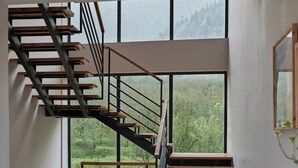 A modern interior with a spiral staircase, large windows, and a view of greenery.