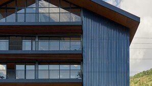 A modern building with a sloped roof, large windows, and a wooden facade.