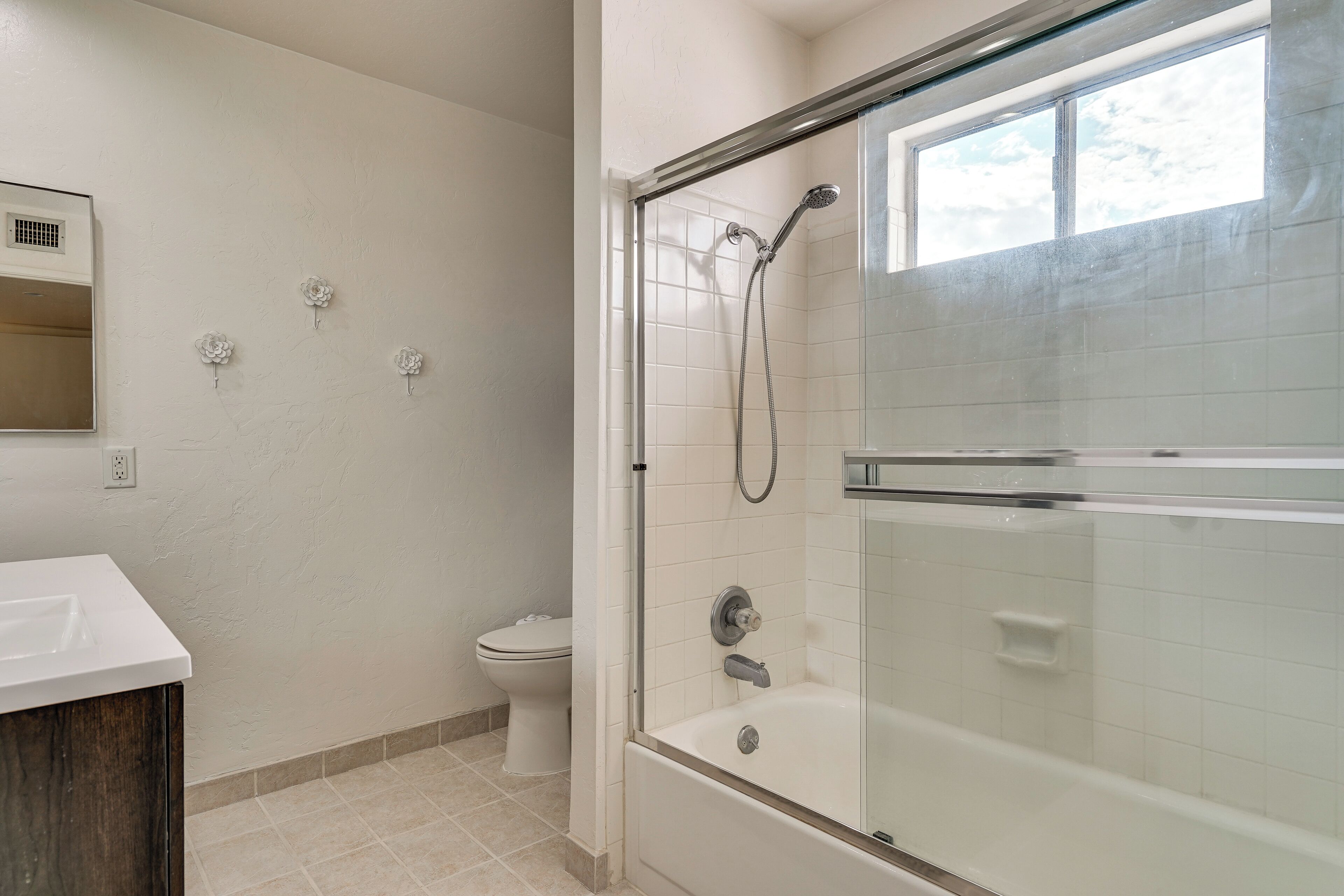 A bathroom with a glass-enclosed shower, a toilet, and a sink.