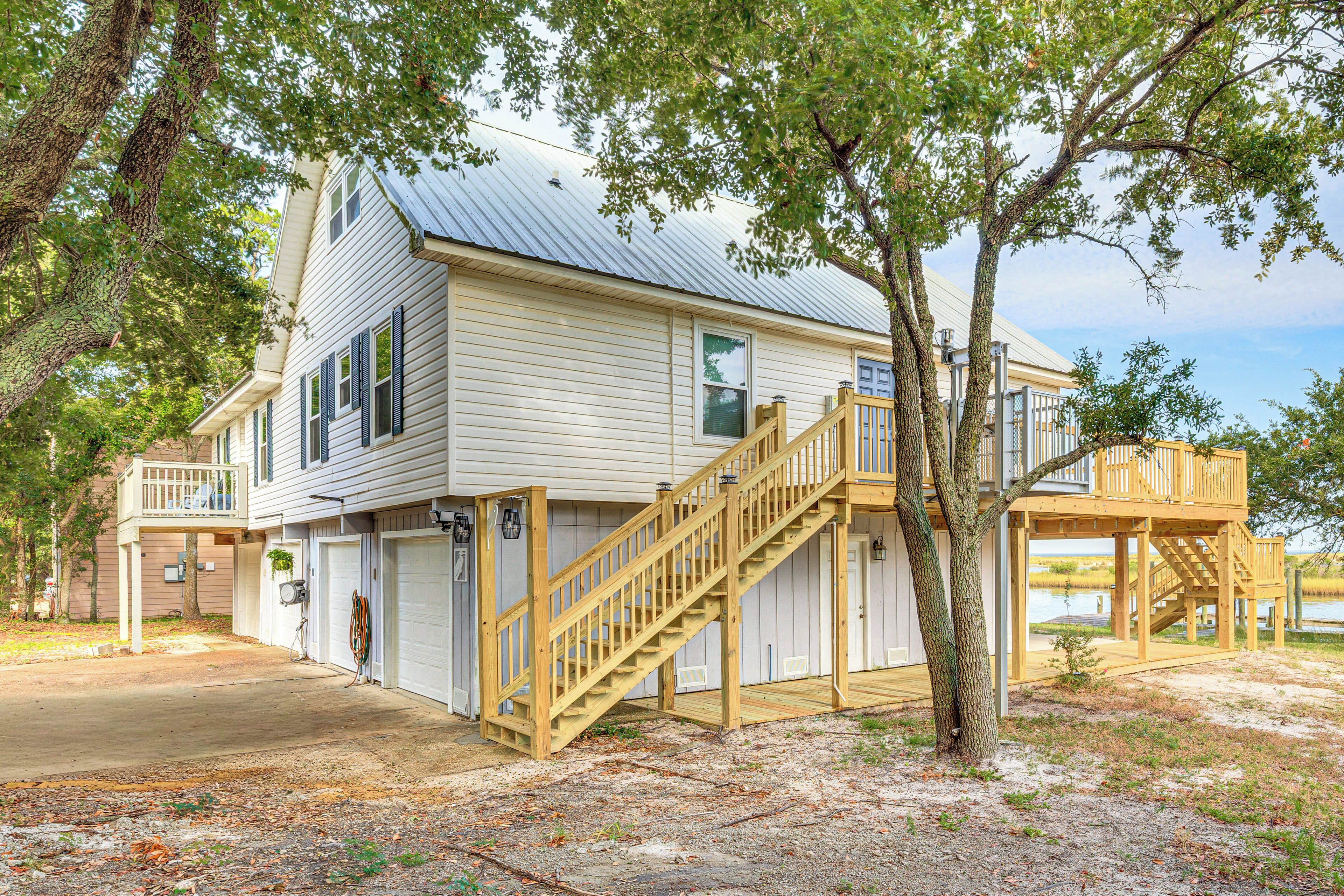 A two-story house with a wooden staircase leading to a deck.
