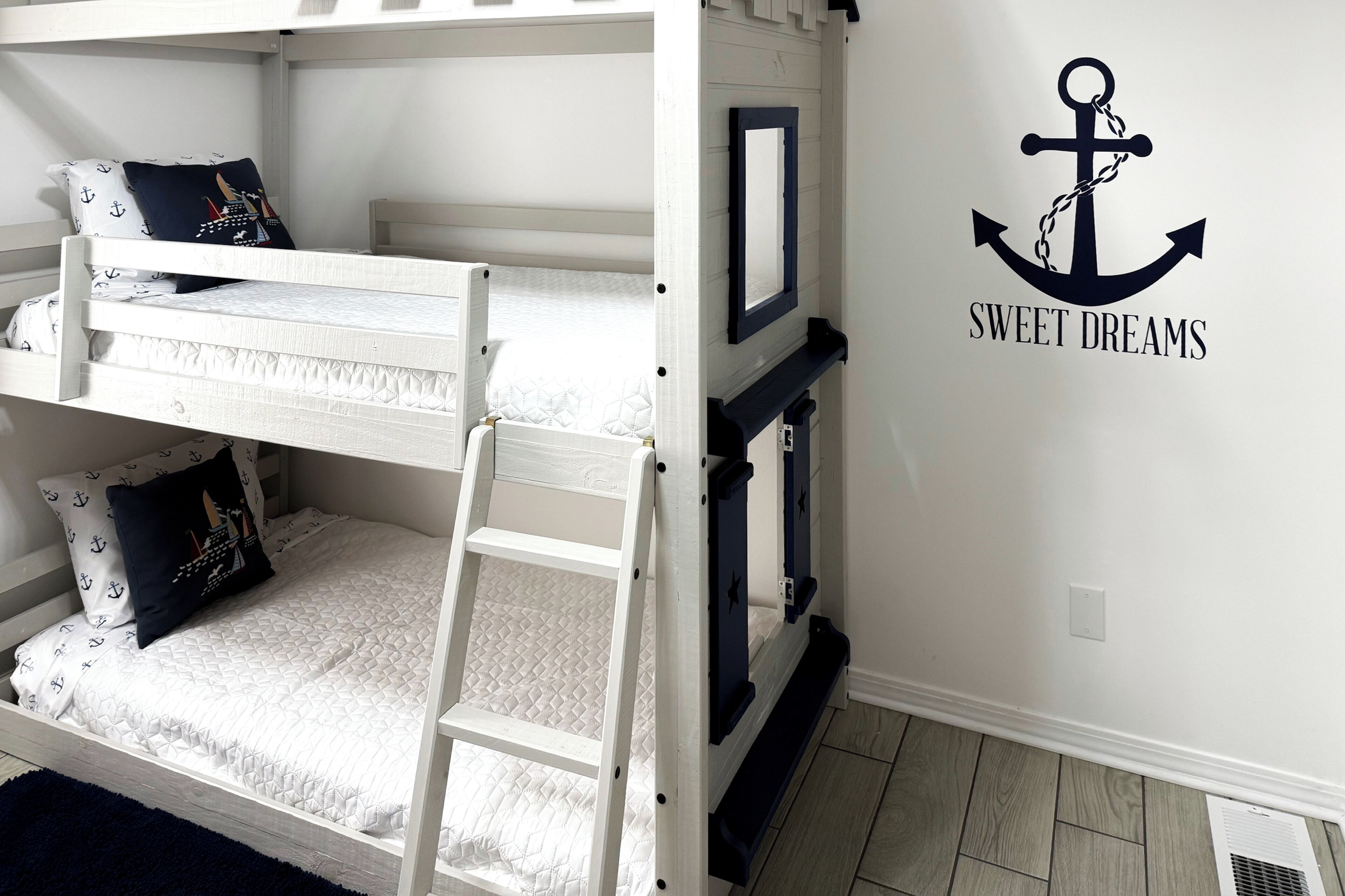 Una litera con escalera, almohada azul oscuro y colchón blanco.