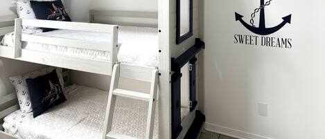 Una litera con escalera, almohada azul oscuro y colchón blanco.