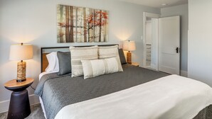 Ein Schlafzimmer mit einem Bett, zwei Nachttischen, einem Wandbild und einer Tür.
