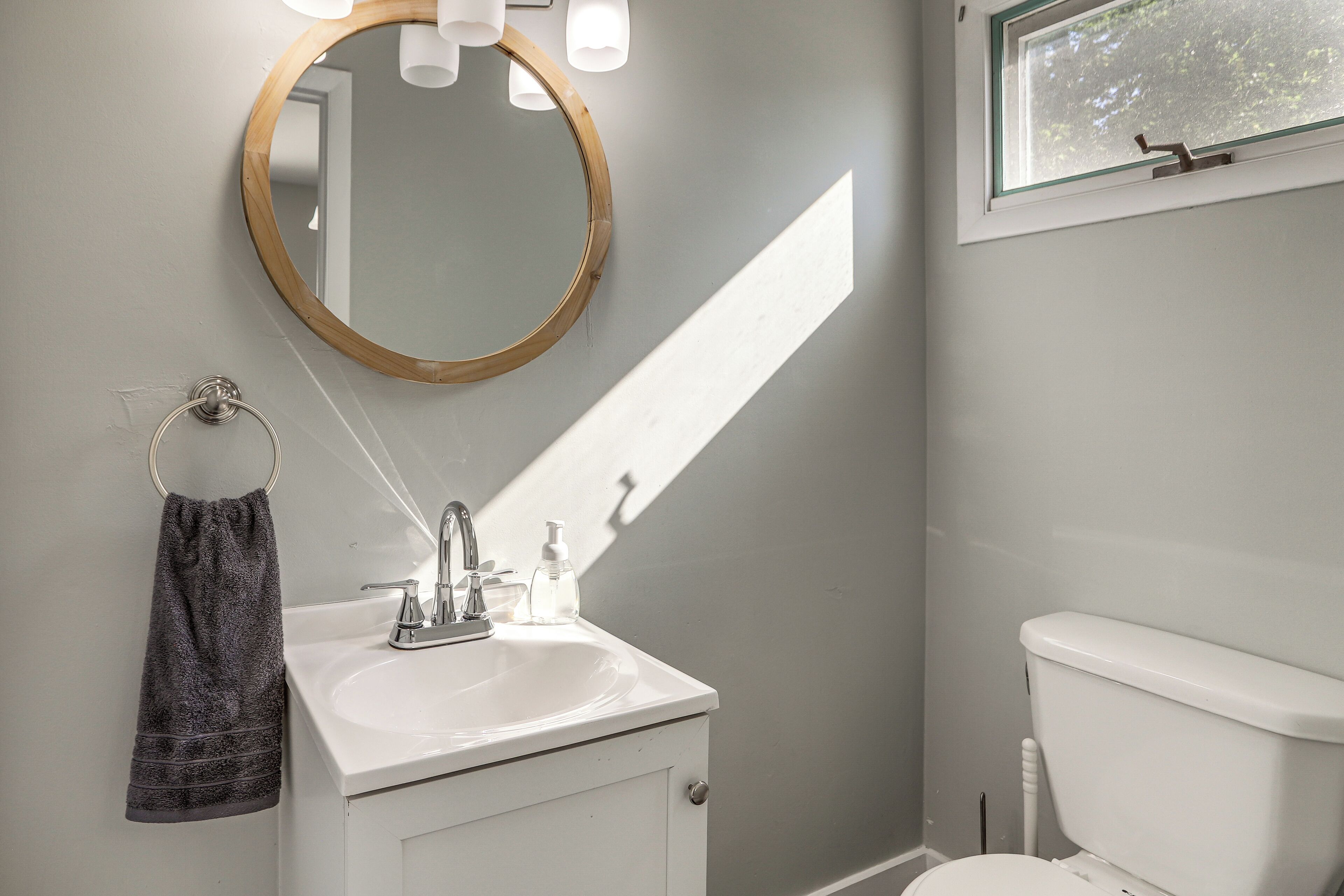 A bathroom with a white sink, a mirror, a towel, and a toilet.