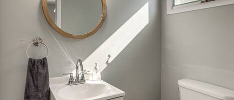 A bathroom with a white sink, a mirror, a towel, and a toilet.