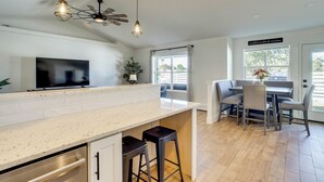 Een moderne keuken met een groot eiland, barstoelen en een eethoek met een bank en stoelen.