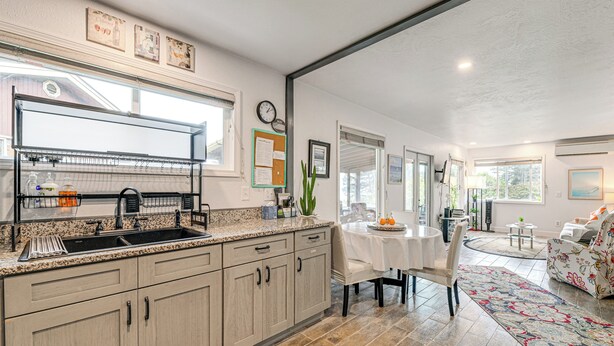 A modern kitchen with granite countertops, a built-in dishwasher, and a dining area with a round table and chairs. - Fish & Hike: Quiet Smith River Cabin Near Ocean! (Smith River)