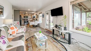 A modern living room with a sofa, coffee table, and a TV mounted on the wall. - Fish & Hike: Quiet Smith River Cabin Near Ocean! (Smith River)
