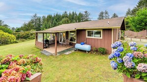 A single-story house with a covered patio, a barbecue grill, and a garden with hydrangeas. - Fish & Hike: Quiet Smith River Cabin Near Ocean! (Smith River)