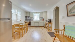 A spacious kitchen with wooden chairs, a dining table, and a refrigerator. - Home w/ Private Yard in Rocky Point (Rocky Point)