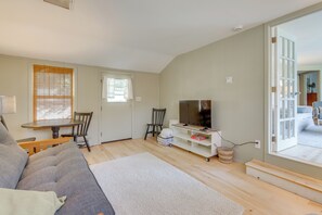 A living room with a sofa, TV, and a dining table with chairs. - Home w/ Private Yard in Rocky Point (Rocky Point)