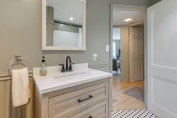 A bathroom with a white sink, wooden vanity, and a mirror.