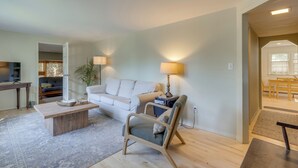 A living room with a sofa, a wooden coffee table, a lamp, and a chair. - Home w/ Private Yard in Rocky Point (Rocky Point)