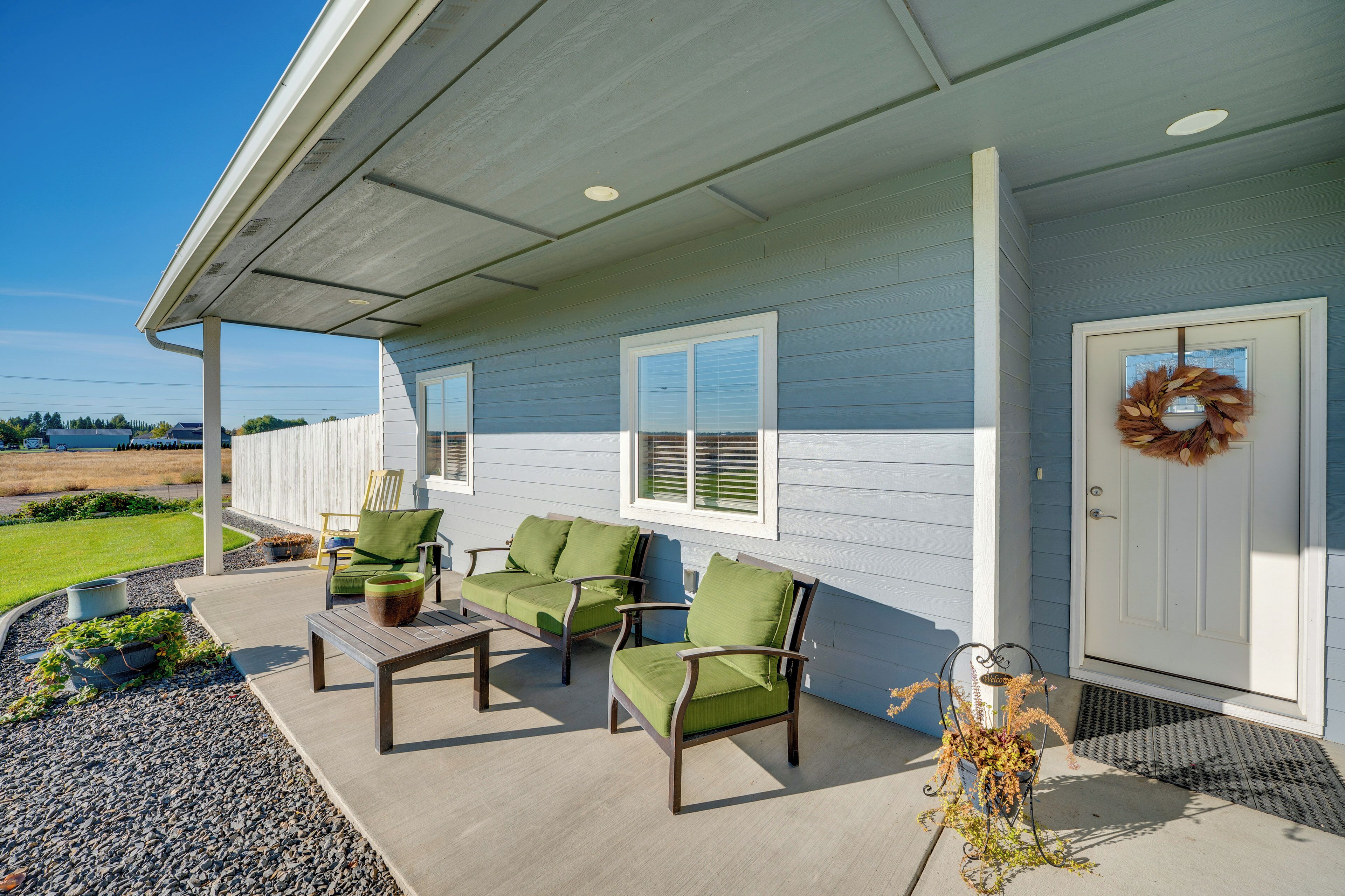 A covered porch with outdoor furniture and a door with a wreath.