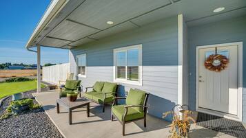 A covered porch with outdoor furniture and a door with a wreath.