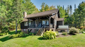 A log cabin with a covered porch, a staircase, and a fire pit area. - Private Spring-fed Pond: Idyllic Shrewsbury Cabin! (Shrewsbury)