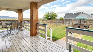 A covered patio with outdoor furniture, a wooden fence, and a view of a house and landscape. - Hiking Nearby! Mountain-view Home Outside ABQ (Edgewood)