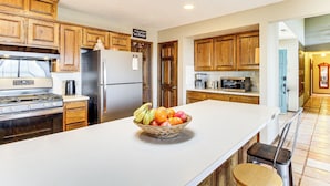 A kitchen with wooden cabinets, a stainless steel refrigerator, a stove, and a fruit bowl on the counter. - Hiking Nearby! Mountain-view Home Outside ABQ (Edgewood)
