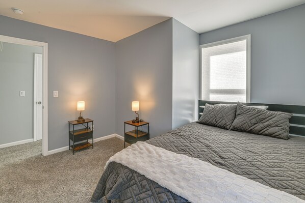 A bedroom with a bed, two bedside tables with lamps, a door, and a window. - Walk to Main Street! Updated Norwich Home (Norwich)