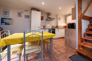 Une cuisine équipée d’une table à manger, de chaises, d’une cuisinière et d’une horloge murale.