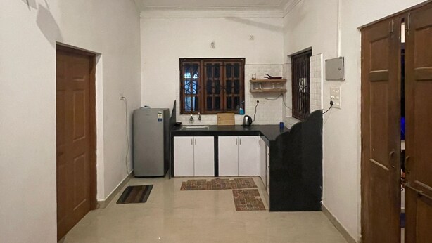 A narrow hallway with a ceiling fan, a refrigerator, a sink, and cabinets. - Urban Mad – Villas & Studio (Morjim)